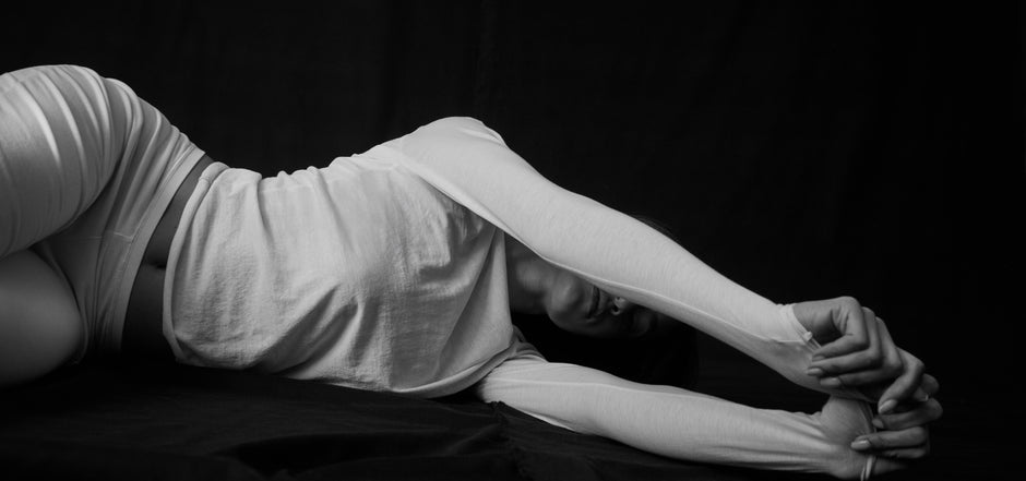 woman stretching in cotton long sleeve top and pants in black and white photography